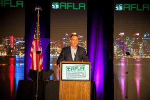 Speaker behind podium at AFLA meeting with custom LED panels behind him