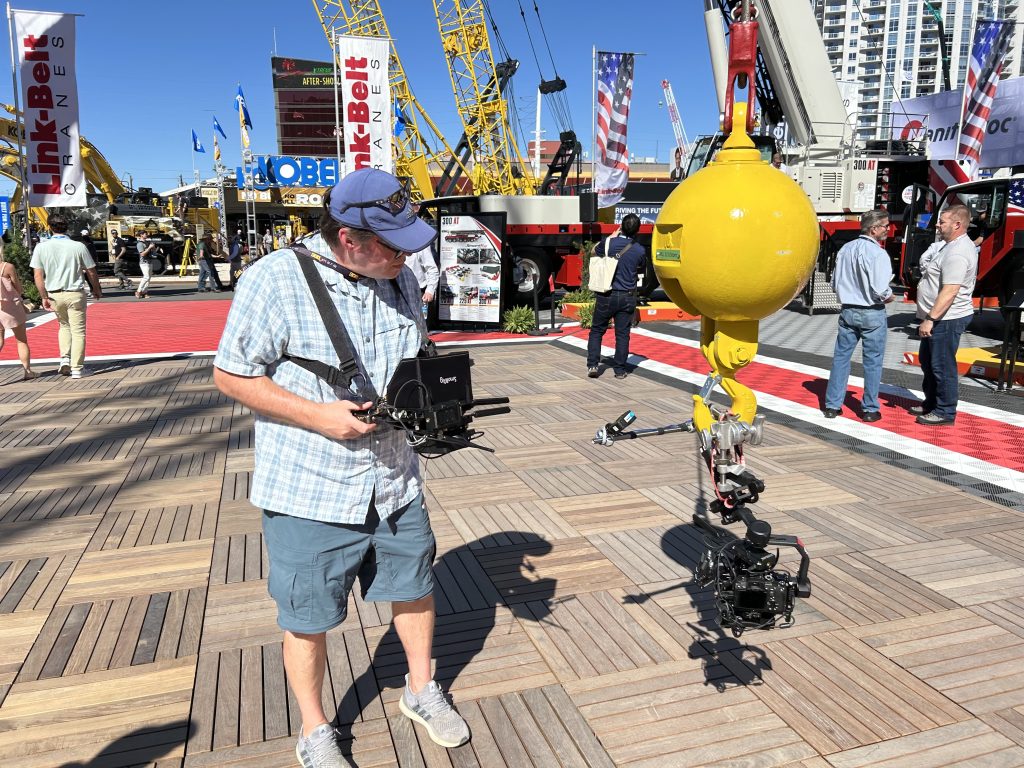 A videographer attaching a camera to a crane to capture aerial video at Conexpo-Con/Agg 2026.