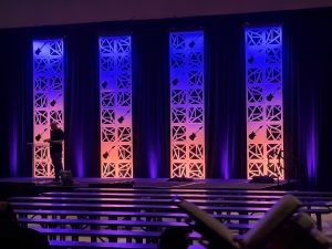 A view from back-of-house at the AHTD 2026 Spring Conference in Nashville, Tennessee. Features a view of the enhances set columns lit in sunset colors.