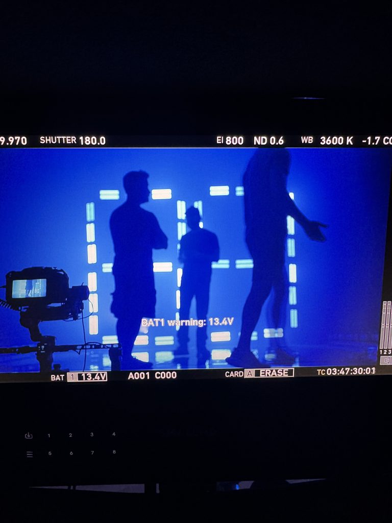 For gallery page: A photo from Behind-the-scenes at the Marquette Basketb all 2025 intro video shoot. Depicts a video screen view of a camera recording the crew setting up the LED number set. 
