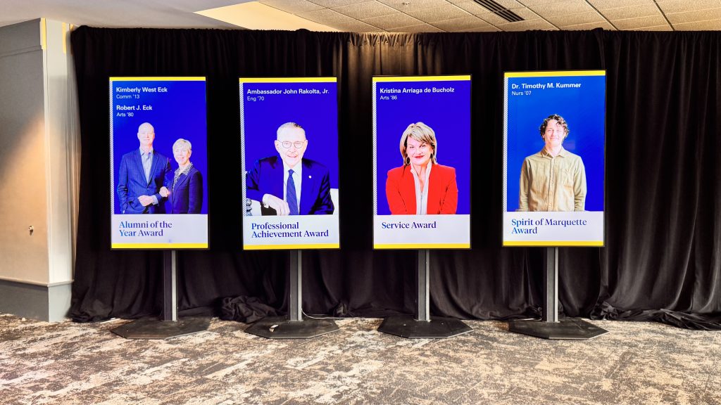 For gallery page: A photo from the Marquette University Alumni National Awards. Features 4 LED monitors in the hallway leading to the event with the 4 winners. 