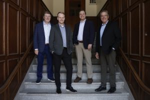 Tri-Marq founders and managing partners pose for a picture on stairs.