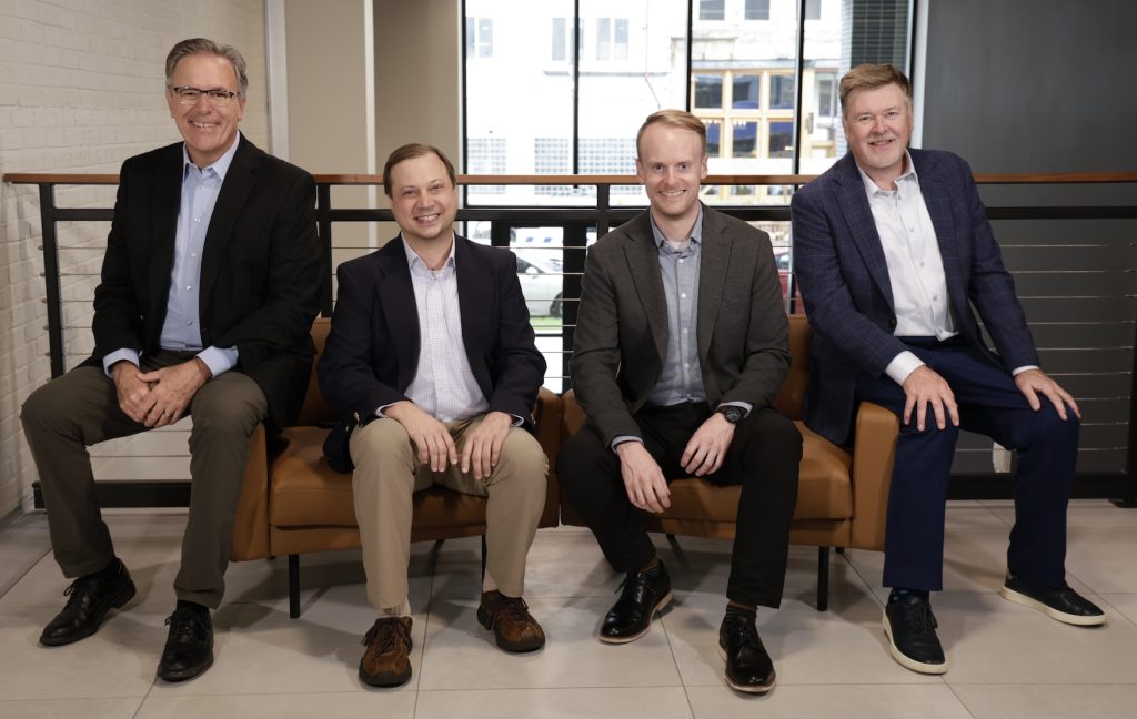 Tri-Marq founders, Jim and Chris, sit with managing partners, Eric and Keith, for a photo in the Eagleknit office building, where the Tri-Marq headquarters is located in Milwaukee.