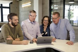 Employees gathered around a laptop talking strategy.