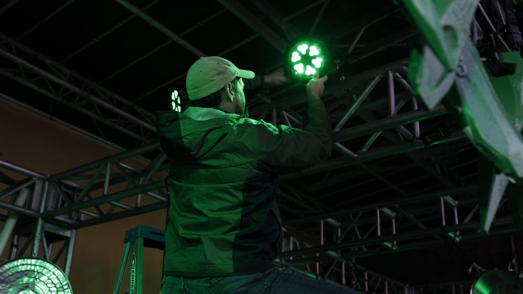 Event Crew Shot. A Technical Director positioning a light during event setup.