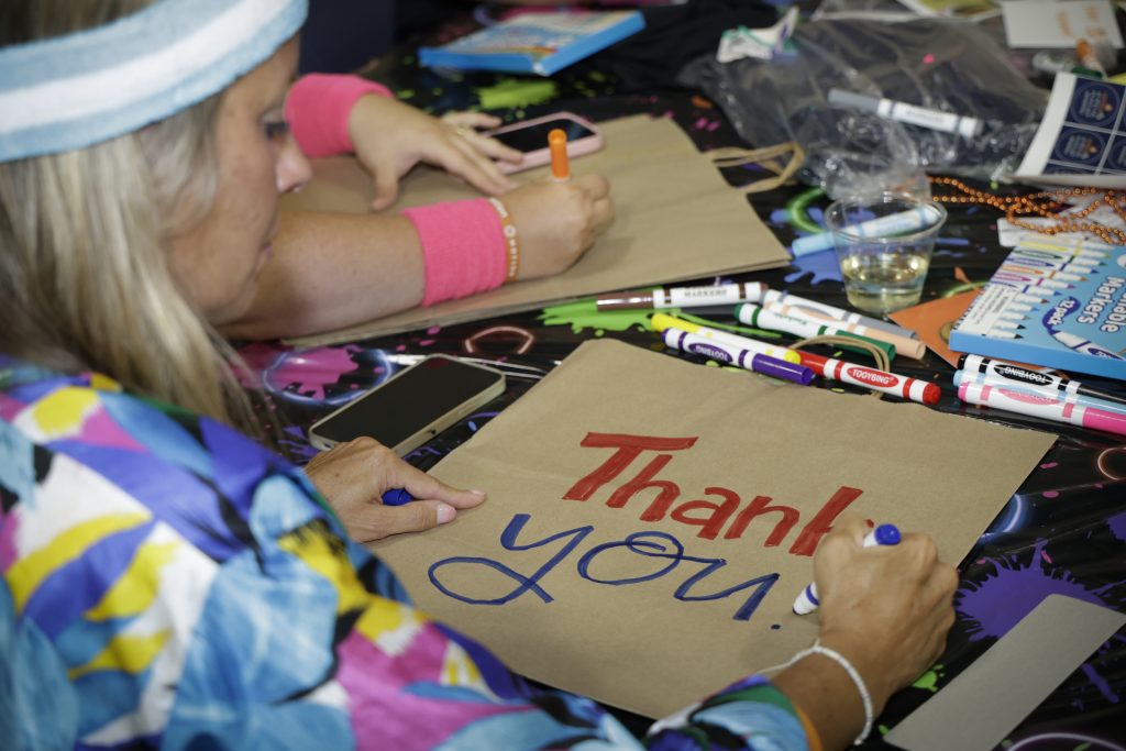 Event photography captures a woman drawing a "Thank You" sign at Numotion's Commercial Growth Summit.